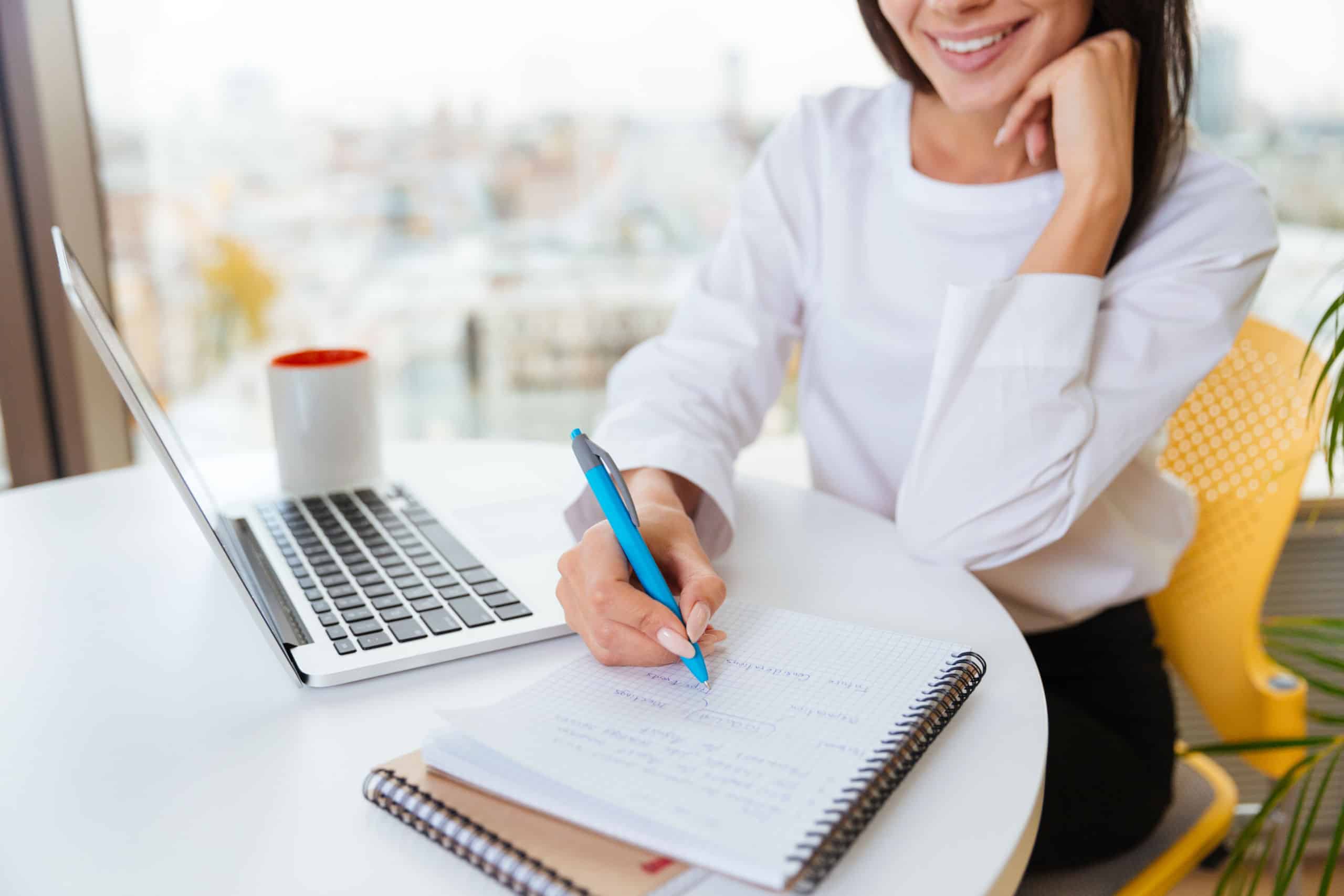 Graphicstock Smiling Young Businesswoman Writing And Using Laptop In Office HUPx9jDXO3x Scaled 